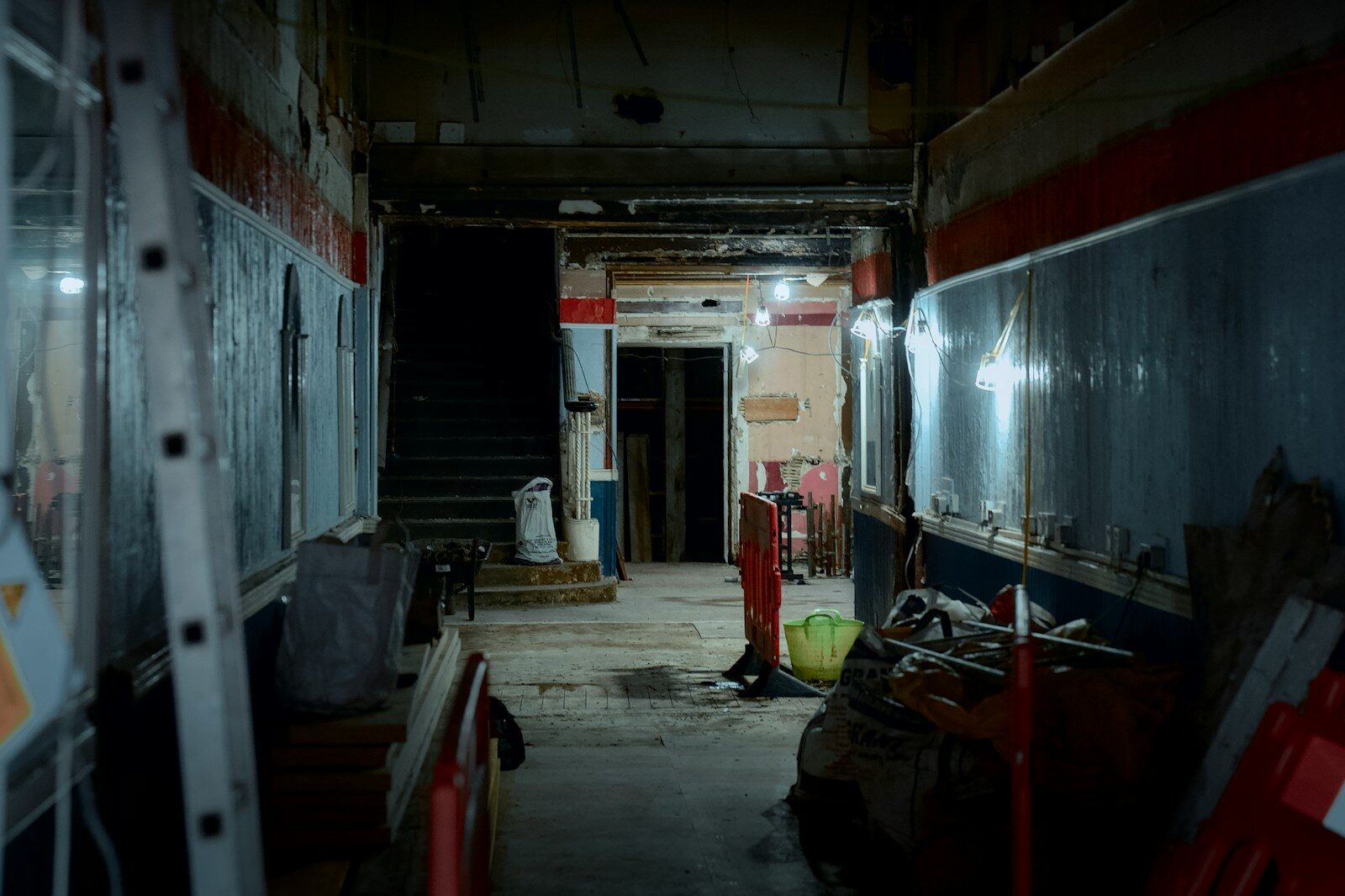 Dimly lit hallway with construction materials and debris.